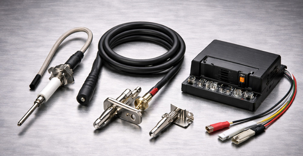 Componentes de un sistema de encendido industrial: electrodo de chispa, cable, piloto de gas y módulo de encendido